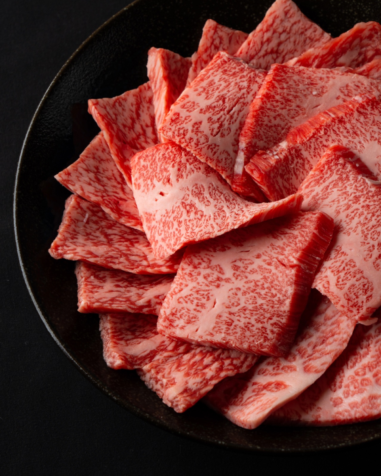 Japanese black wagyu beef slices served on a dark plate